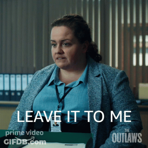 A Woman Is Sitting At A Desk With The Words " Leave It To Me " On The Screen GIF