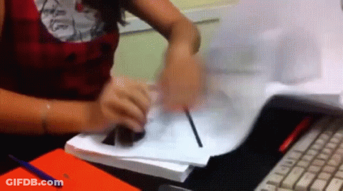A Woman Is Sitting At A Desk Writing On A Piece Of Paper With A Pen GIF