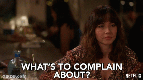 A Woman Is Sitting At A Table And Says What 'S To Complain About Netflix GIF