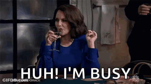 A Woman Is Sitting At A Table Drinking A Glass Of Wine And Saying I 'M Busy . GIF