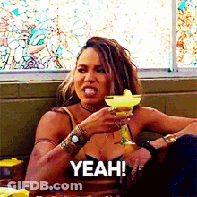 A Woman Is Sitting At A Table Drinking A Margarita And Says Yeah . GIF