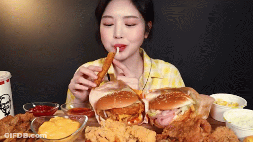 A Woman Is Sitting At A Table Eating A Bunch Of Fried Food . GIF