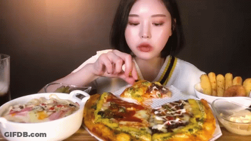 A Woman Is Sitting At A Table Eating A Pizza . GIF