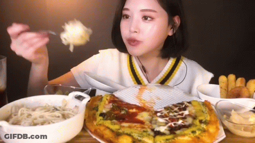 A Woman Is Sitting At A Table Eating A Pizza With A Fork And Spoon . GIF