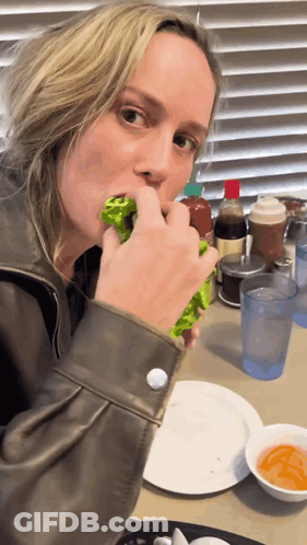 A Woman Is Sitting At A Table Eating A Salad GIF