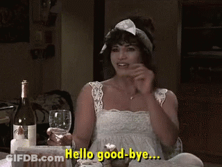 A Woman Is Sitting At A Table Holding A Glass Of Wine And Saying Hello Good-Bye .. GIF