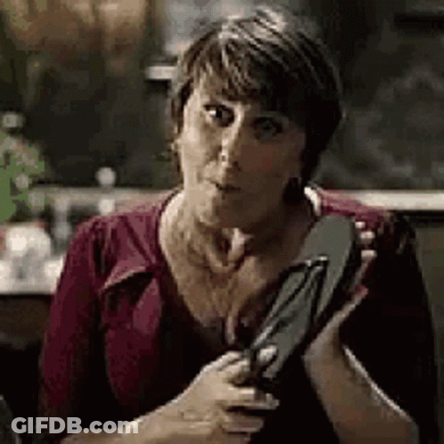 A Woman Is Sitting At A Table Holding A Pair Of Flip Flops . GIF