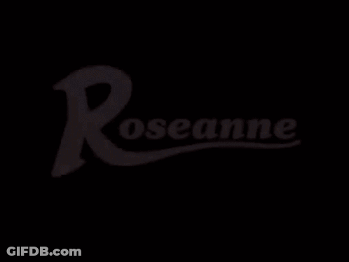 A Woman Is Sitting At A Table Holding A Piece Of Paper In Her Hands GIF