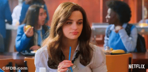 A Woman Is Sitting At A Table In A Cafeteria Drinking Through A Blue Straw . GIF