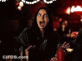 A Woman Is Sitting At A Table In A Dark Room With A Ketchup Bottle . GIF