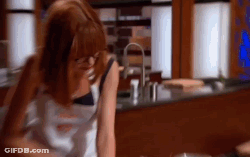 A Woman Is Sitting At A Table In A Kitchen Talking On A Phone . GIF