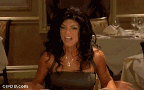 A Woman Is Sitting At A Table In A Restaurant Holding A Glass Of Liquid . GIF
