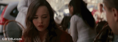 A Woman Is Sitting At A Table In A Restaurant With Her Eyes Closed And A Man Is Standing Behind Her . GIF