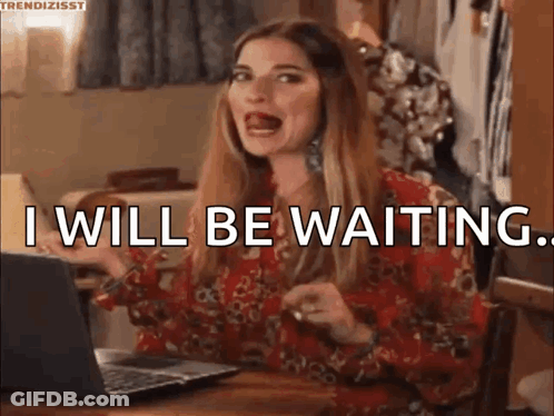 A Woman Is Sitting At A Table In Front Of A Laptop Computer And Saying `` I Will Be Waiting '' . GIF