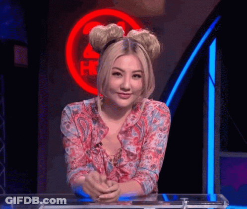 A Woman Is Sitting At A Table In Front Of A Sign That Says ' Hot ' GIF