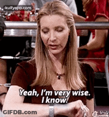 A Woman Is Sitting At A Table Looking At Her Watch And Saying Yeah , I 'M Very Wise . GIF