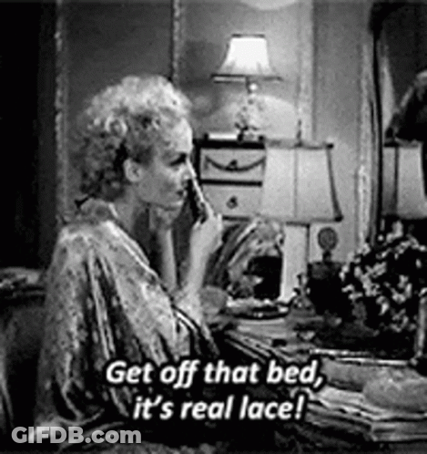 A Woman Is Sitting At A Table Talking On A Cell Phone In A Bedroom . GIF