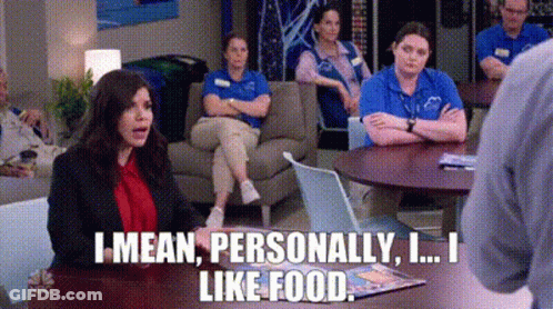 A Woman Is Sitting At A Table Talking To A Man While A Group Of People Sit On A Couch . GIF