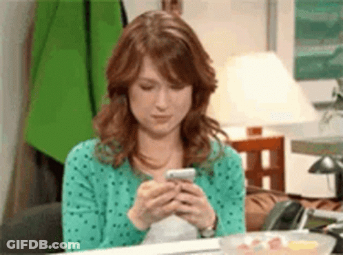 A Woman Is Sitting At A Table Using A Cell Phone . GIF
