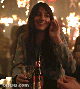 A Woman Is Sitting At A Table With A Bottle Of Coke GIF