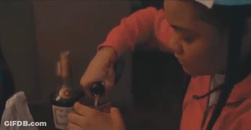 A Woman Is Sitting At A Table With A Bottle Of Wine In Her Hands . GIF