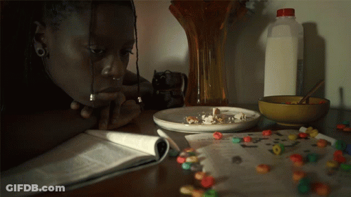 A Woman Is Sitting At A Table With A Bowl Of Cereal And A Bottle Of Milk GIF