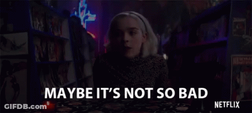 A Woman Is Sitting At A Table With A Candle In Front Of A Bookshelf In A Bookstore . GIF