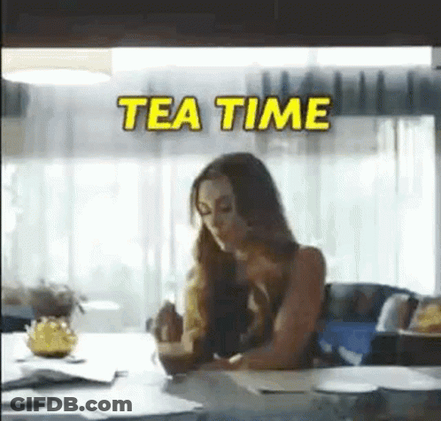 A Woman Is Sitting At A Table With A Cup Of Tea In Her Hand . GIF