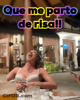 A Woman Is Sitting At A Table With A Glass Of Beer And A Sign That Says Que Me Parto De Risa !! GIF