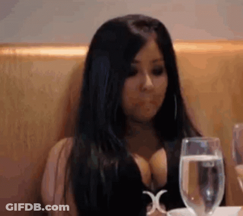 A Woman Is Sitting At A Table With A Glass Of Water And A Glass Of Wine . GIF