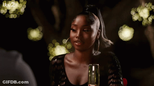 A Woman Is Sitting At A Table With A Glass Of Wine And It 'S 2 On The Bottom Right GIF