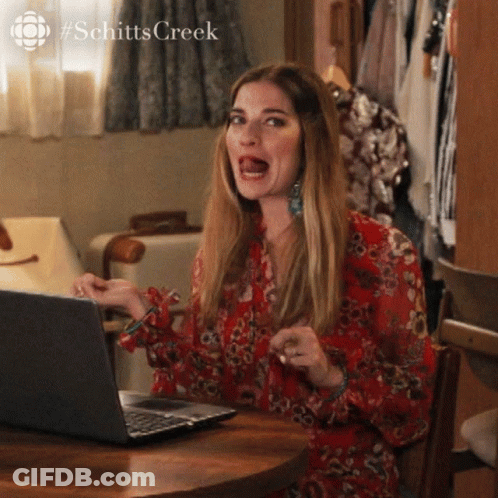 Woman Sitting At Table With Laptop Making Funny Face GIF