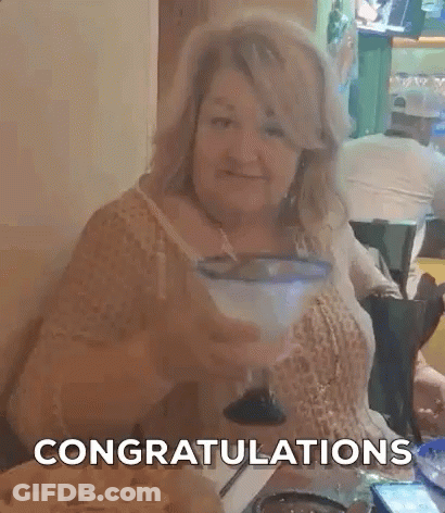 A Woman Is Sitting At A Table With A Margarita In Her Hand And The Words `` Congratulations '' Behind Her . GIF