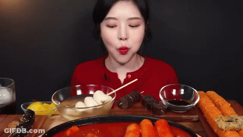 A Woman Is Sitting At A Table With A Plate Of Food And A Bowl Of Dipping Sauce . GIF
