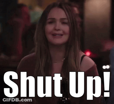 A Woman Is Sitting At A Table With A Sign That Says Shut Up ! GIF