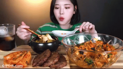 A Woman Is Sitting At A Table With Bowls Of Food And A Glass Of Cola GIF