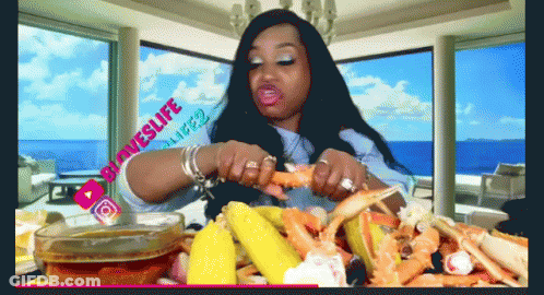 A Woman Is Sitting At A Table With Crab Legs And Corn GIF
