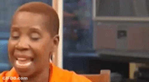 A Woman Is Sitting At A Table With Her Eyes Closed And Laughing . GIF