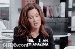 A Woman Is Sitting At A Table With Her Eyes Closed And Saying Yes , I Am I 'M Amazing . GIF