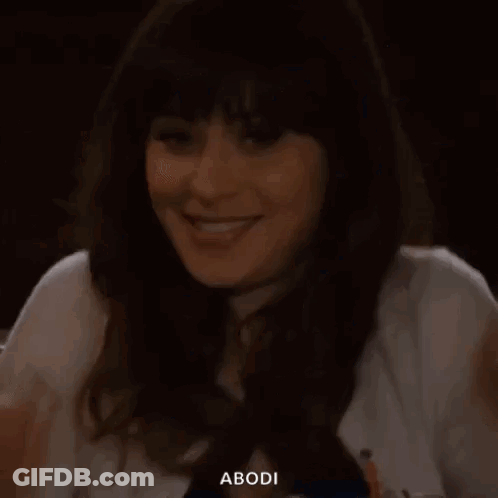 A Woman Is Sitting At A Table With Her Hand On Her Face And Smiling . GIF