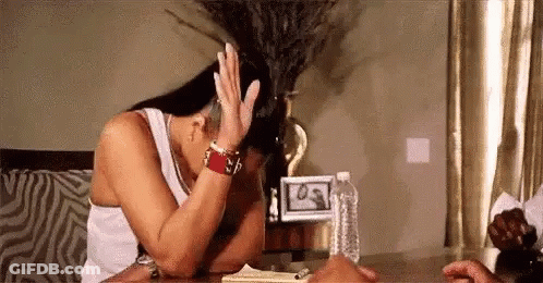 A Woman Is Sitting At A Table With Her Head In Her Hands . GIF
