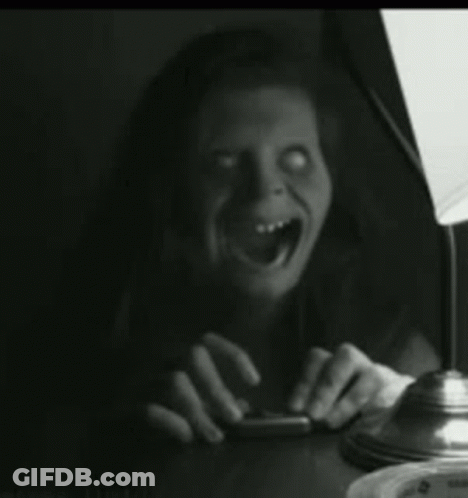 A Woman Is Sitting At A Table With Her Mouth Open And A Lamp In The Background . GIF
