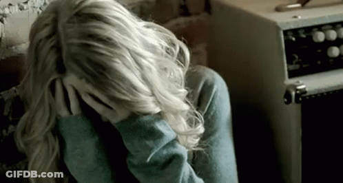 A Woman Is Sitting Down With Her Head In Her Hands . GIF