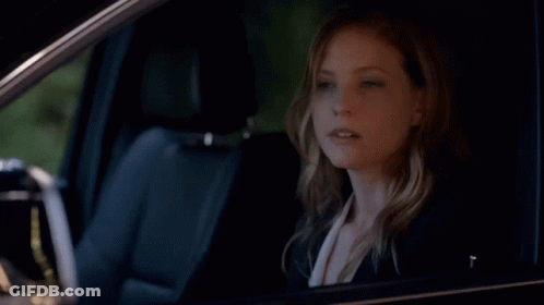 A Woman Is Sitting In A Car And Pointing GIF