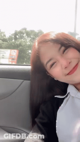 A Woman Is Sitting In A Car And Smiling GIF