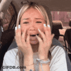 A Woman Is Sitting In A Car Covering Her Mouth With Her Hands GIF