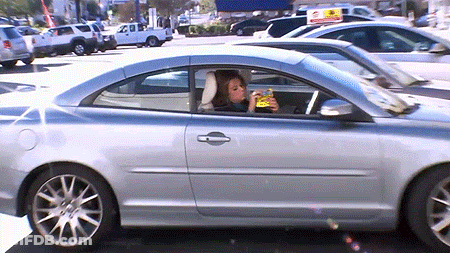 A Woman Is Sitting In A Car Drinking A Beer GIF