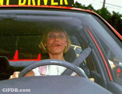 A Woman Is Sitting In A Car Under A Sign That Says " Taxi Driver " GIF