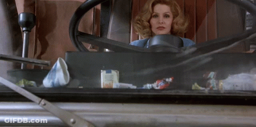 A Woman Is Sitting In A Car With A Steering Wheel GIF