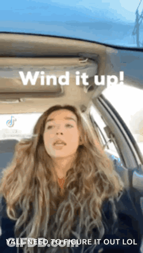 A Woman Is Sitting In A Car With The Words Wind It Up GIF